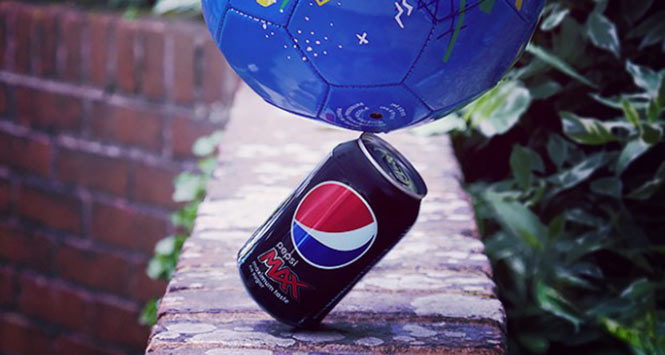Football balancing on can of Pepsi