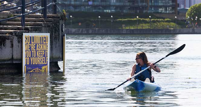 Canoeist reading partially submerged billboard